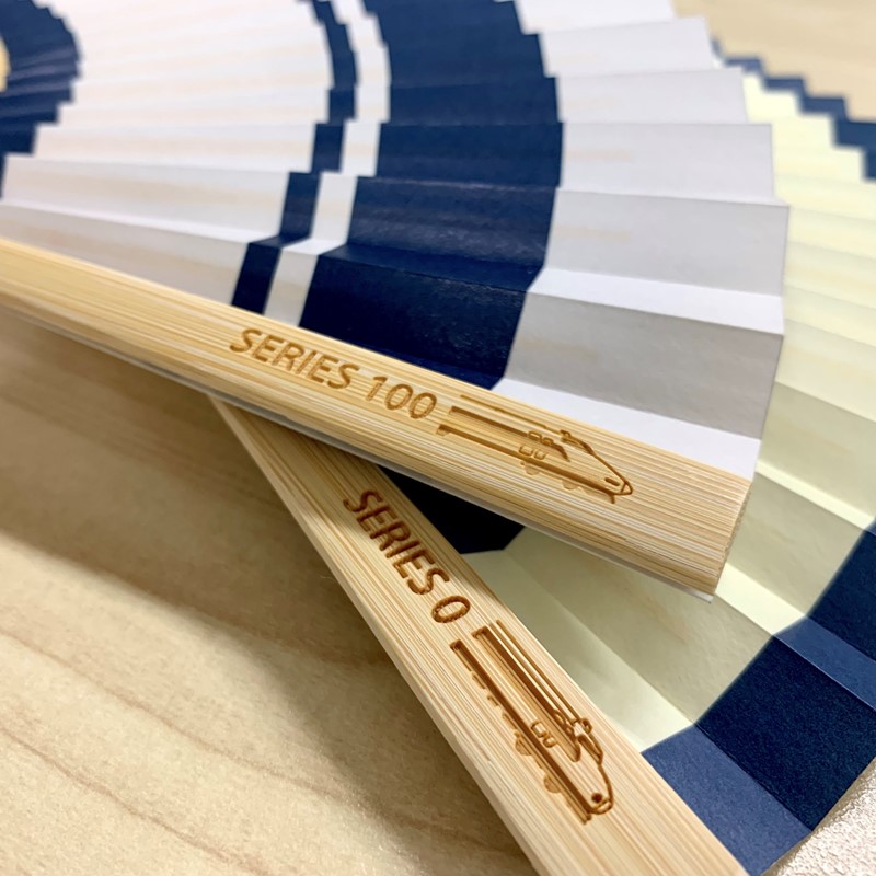 親骨には0系のイラストが彫刻されています。暑い夏の日の普段使いのほか、ギフトとしてもご利用頂けます。
さらに、「オリジナル扇子（白竹堂×新幹線100系）」も同時発売いたします。