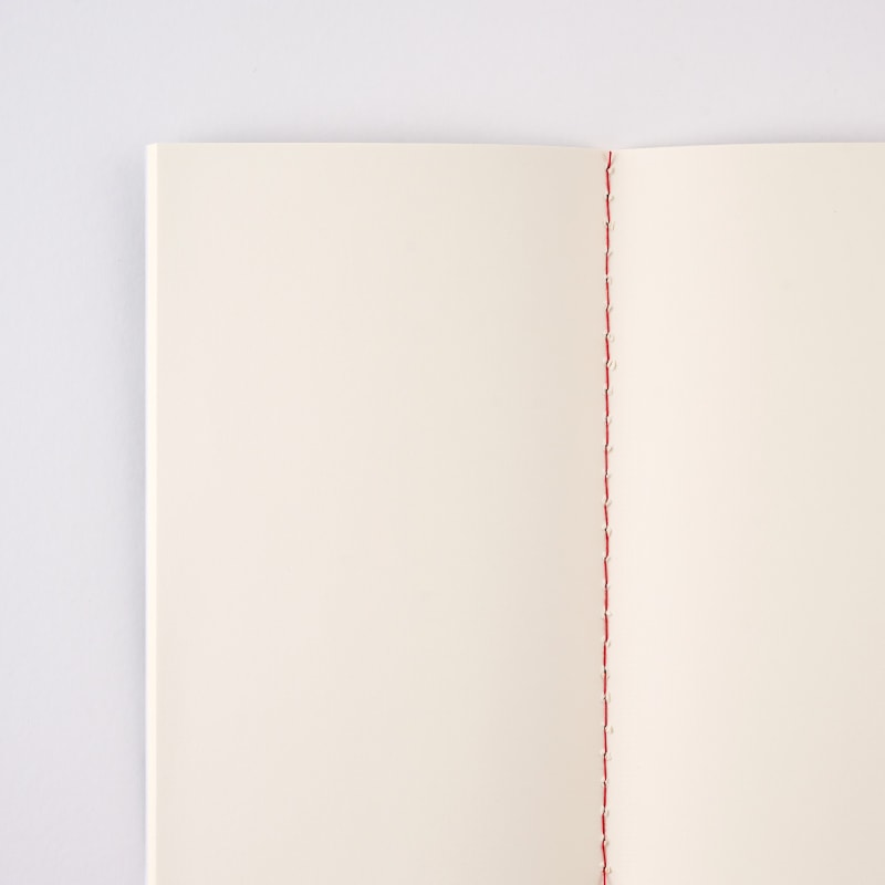 罫線のない無地のノート。綴じ糸の赤が鮮やかです。