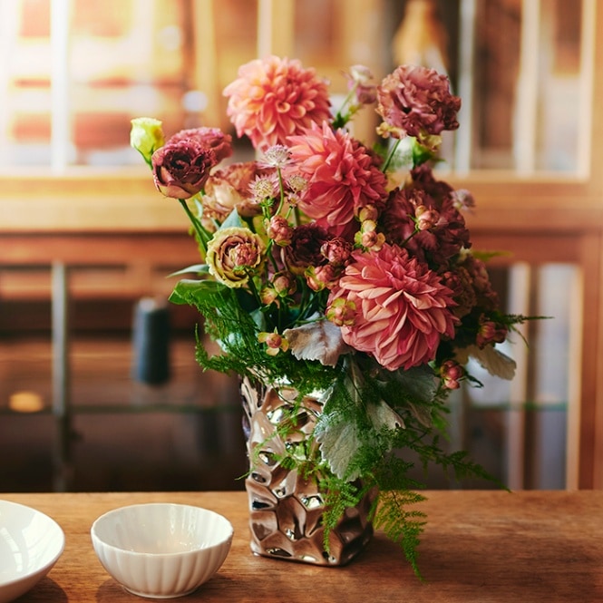 アースカラーの花とメタリックベースのアレンジメント