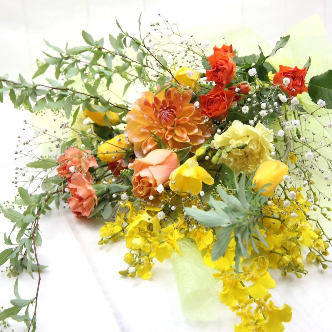 バラとかすみ草をいれたイエロー・オレンジ系の花束