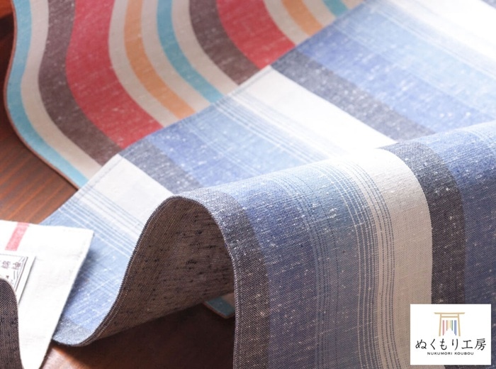 遠州綿紬（えんしゅうめんつむぎ）は、静岡県西部・<br>
遠州地方で古くから受け継がれてきた伝統的な<br>
織物です。最大の特徴は、糸を先に染めてから<br>
織り上げる「先染め」製法。この工程により、<br>
柄に奥行きと立体感が生まれ、使うほどに風合いが<br>
増していきます。<br>